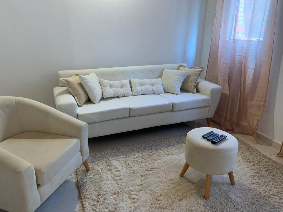 a living room with a white couch and a stool at Hermosa casa, zona Aeropuerto in Luque
