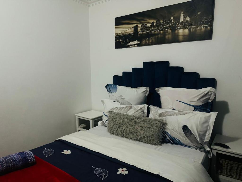 1 dormitorio con 1 cama con cabecero azul y almohadas en Affordable Guest house in Mwobray, en Ciudad del Cabo