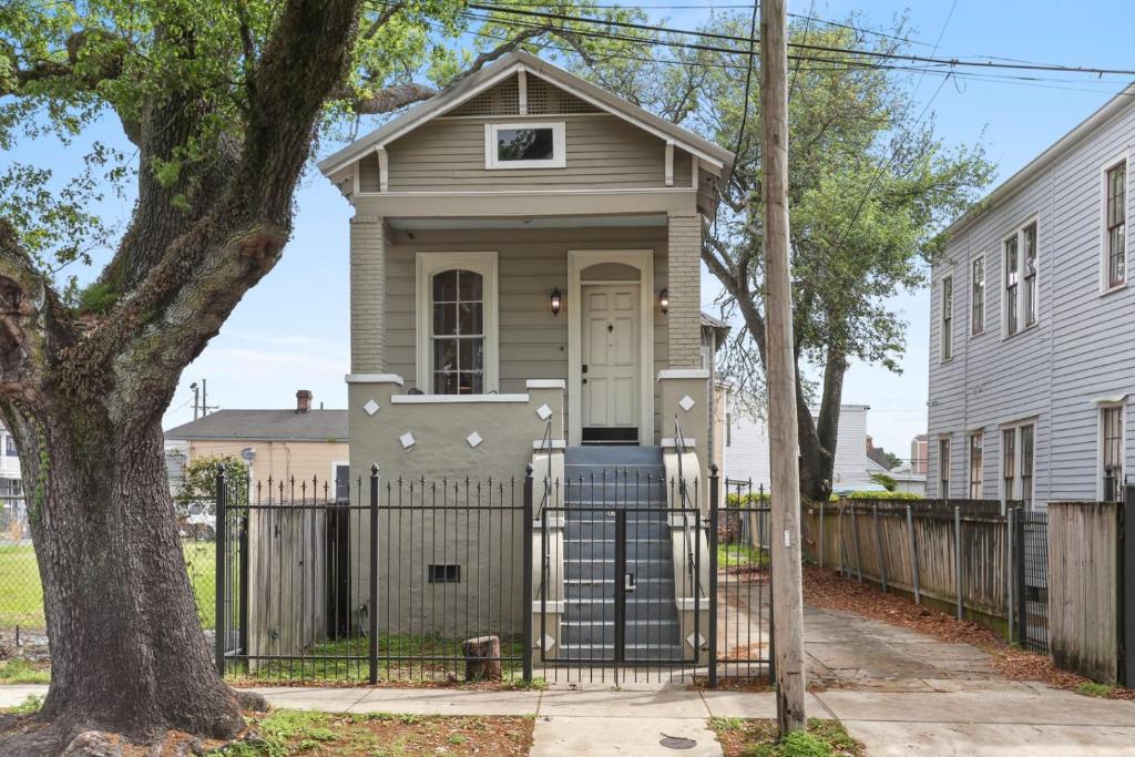 ニューオーリンズにある3BD HOME STEPS TO SAINT CHARLES Gated Parkingの塀と木のある家