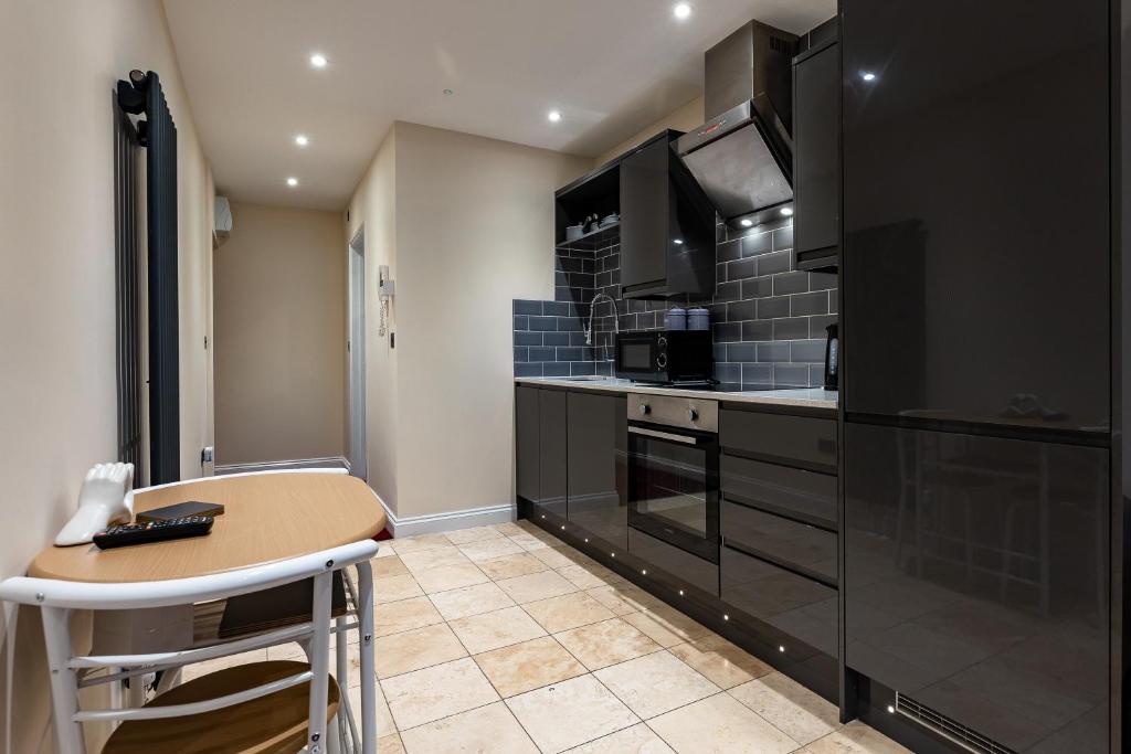 a kitchen with black cabinets and a small table at Cosy Apartment In The Heart of the City in Norwich