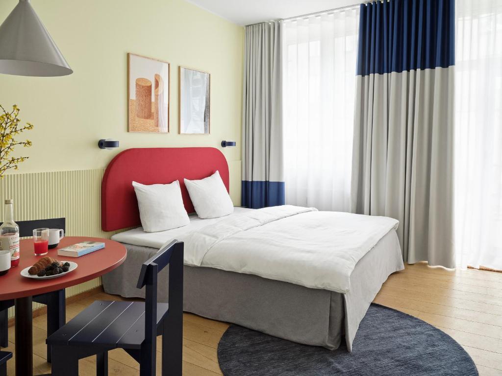 Schlafzimmer mit einem Bett mit einem roten Kopfteil und einem Tisch in der Unterkunft BRIK Apartment Hotel in Kopenhagen