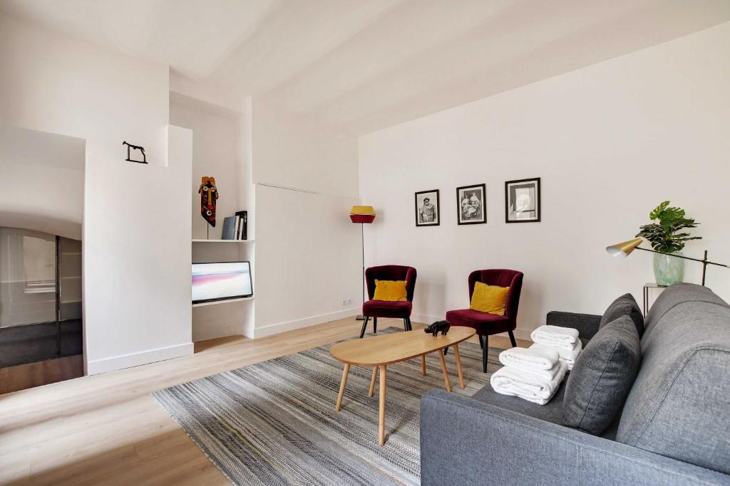 een woonkamer met een bank en 2 stoelen bij Stylish flat in the heart of the city in Parijs