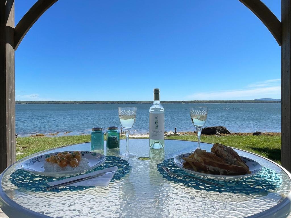 een tafel met twee borden eten en een fles wijn bij Acadia Bay Cottages in Surry