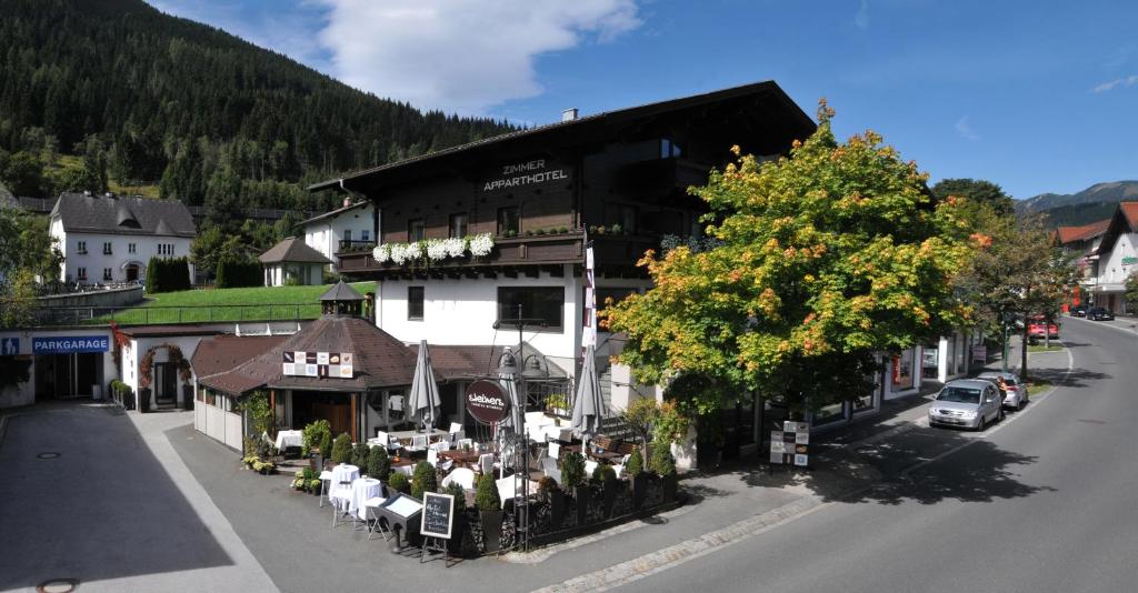 a building on the side of a street with a tree at Apparthotel Restaurant Steiners in Eben im Pongau