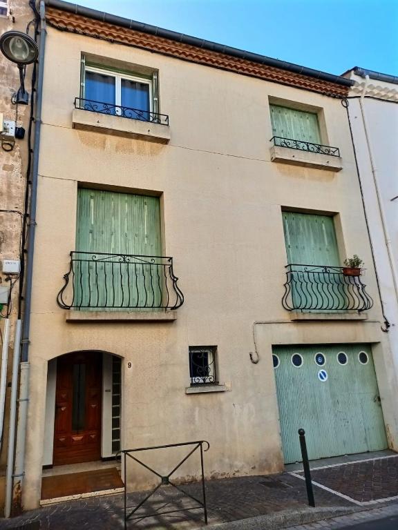 - un bâtiment avec des portes et des balcons verts dans une rue dans l'établissement Mol, à Sérignan