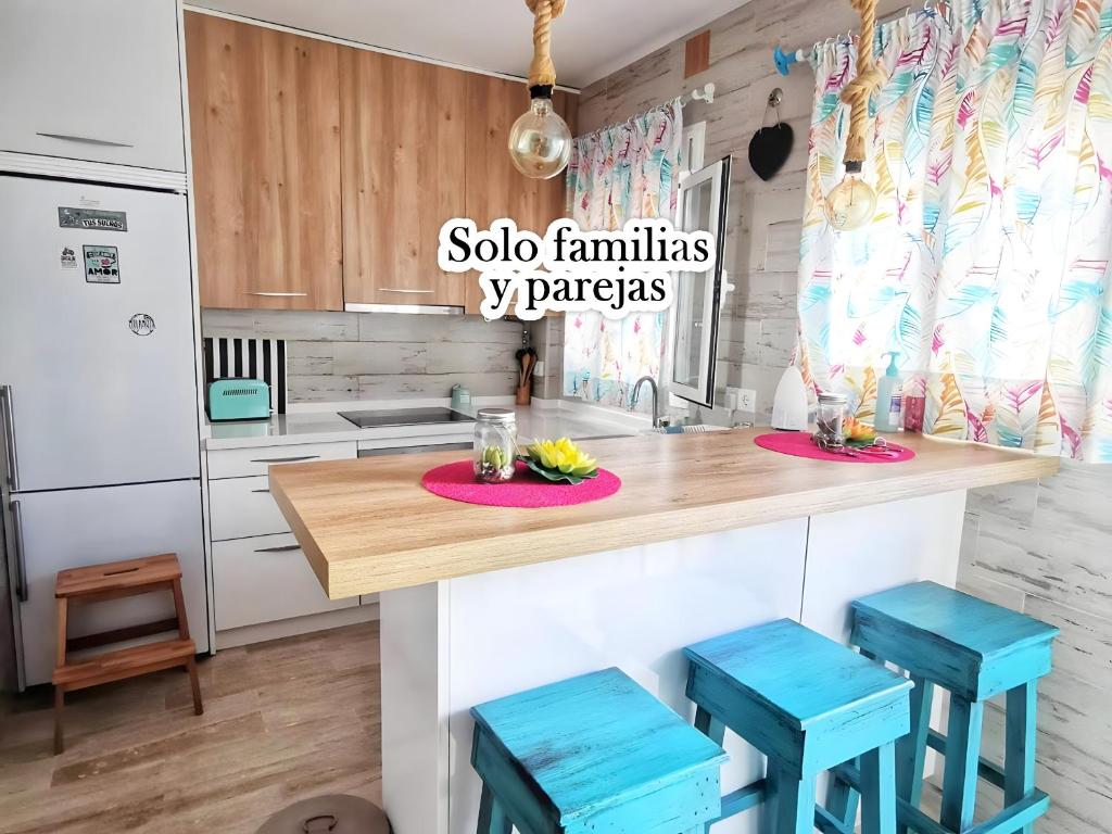 una cucina con bancone in legno e sgabelli blu di Apartamento Agua marina con terraza a Chiclana de la Frontera