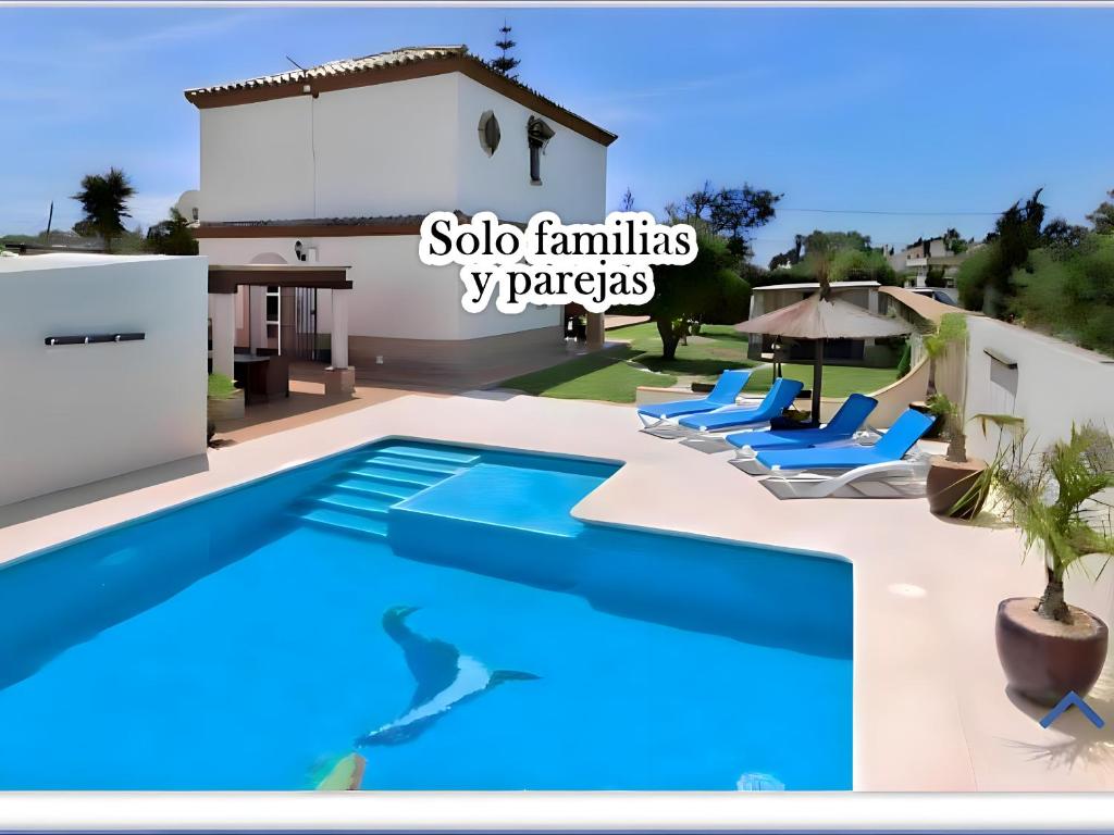 una piscina con sillas y una villa en Villa Encantadora y Espaciosa Piscina Privada y Terraza Exclusivas para Familias, en Conil de la Frontera