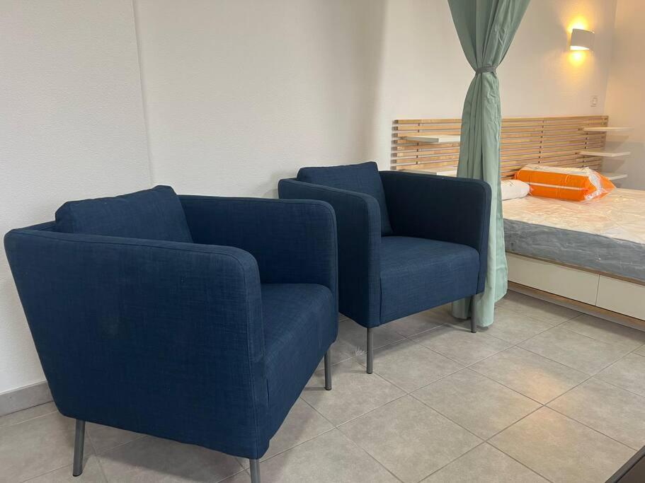 zwei blaue Stühle und ein Bett in einem Zimmer in der Unterkunft Johannesburg in Juvignac