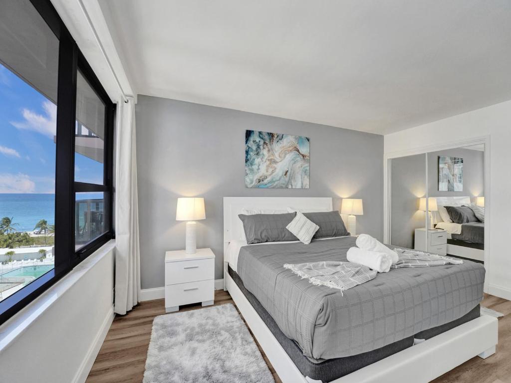 um quarto branco com uma cama e uma grande janela em Awesome Beach Condo with Resort Amenities 1016 em Miami Beach