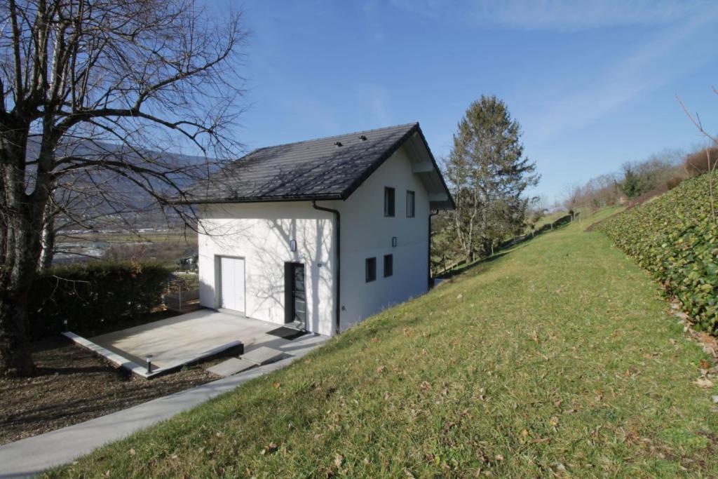 a small white building on a grassy hill at Pretty new and comfortable house between towns and lakes in Voglans