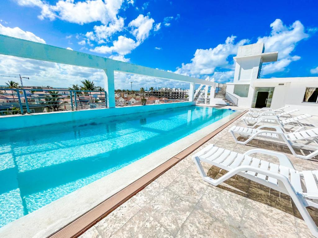 una piscina con tumbonas junto a un edificio en DUKASSI SUITES Hotel ROOMS BEACH Bavaro WIFI Parking ROOFTOP POOL & SPA, en Punta Cana