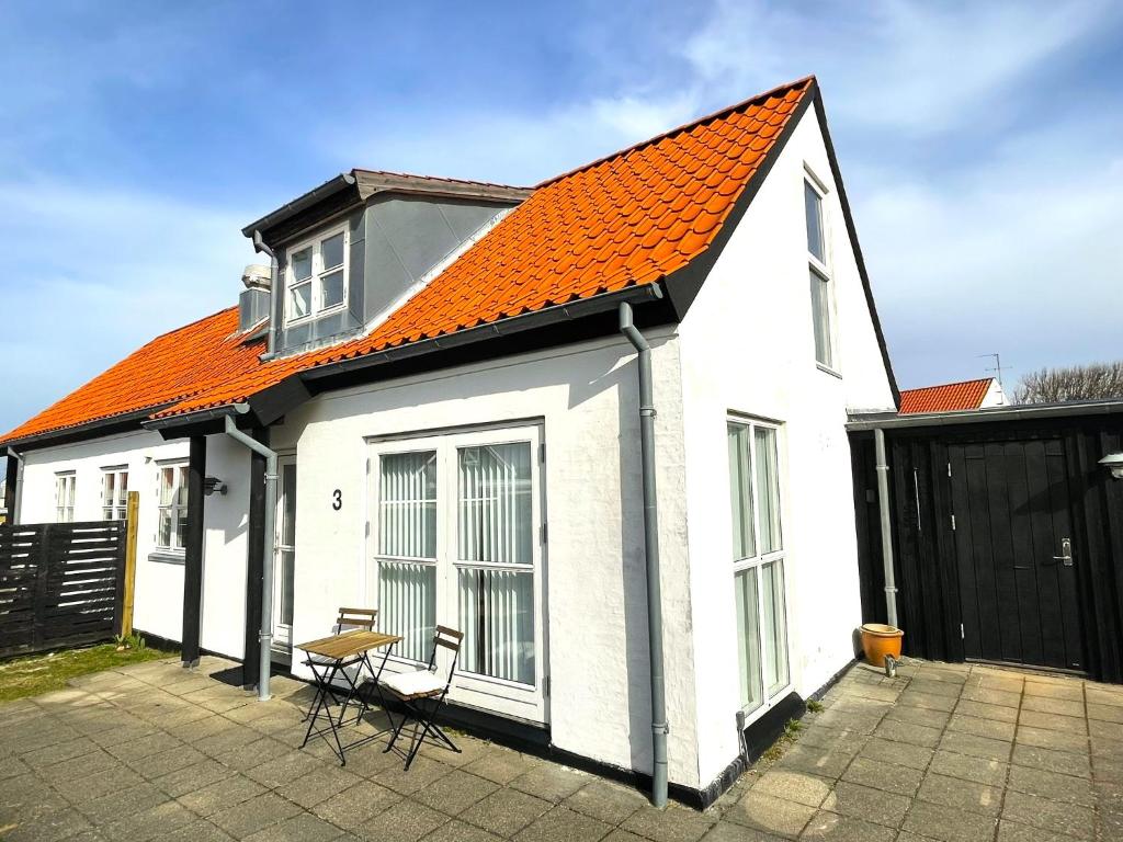 una casa blanca con techo naranja y techo naranja en Byhus centralt på Læsø en Vesterø Havn