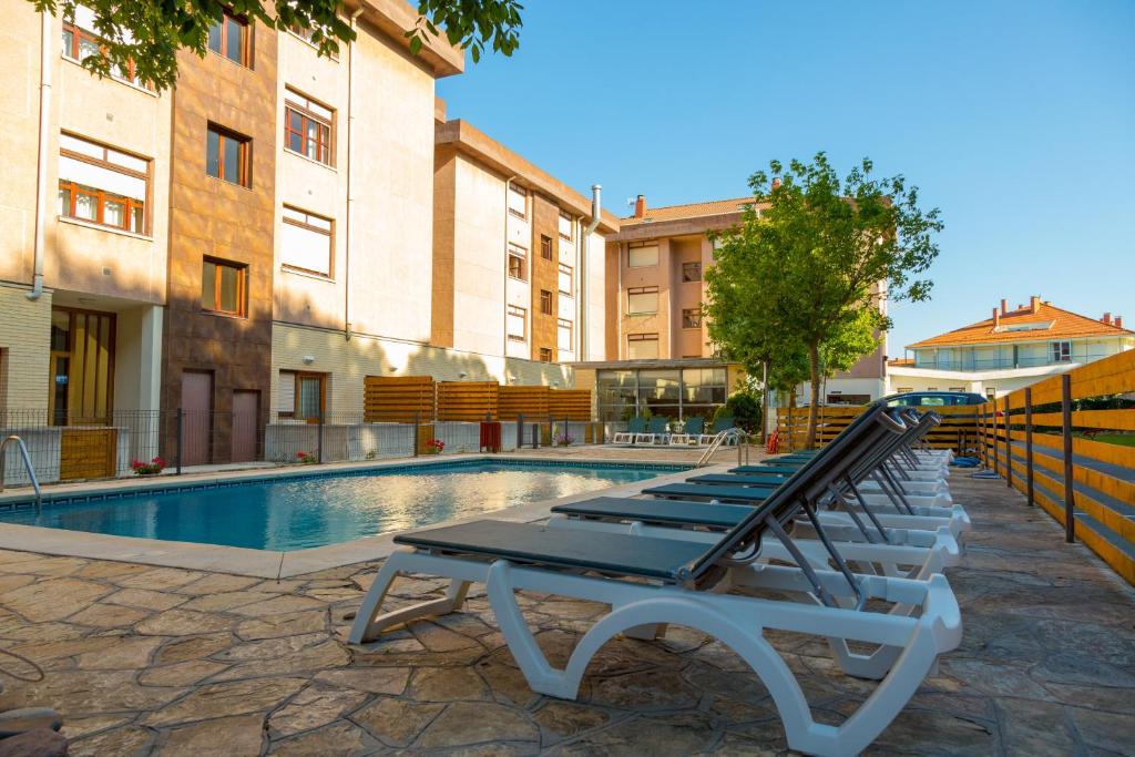 a row of lounge chairs next to a swimming pool at Hotel Los Arces in Isla