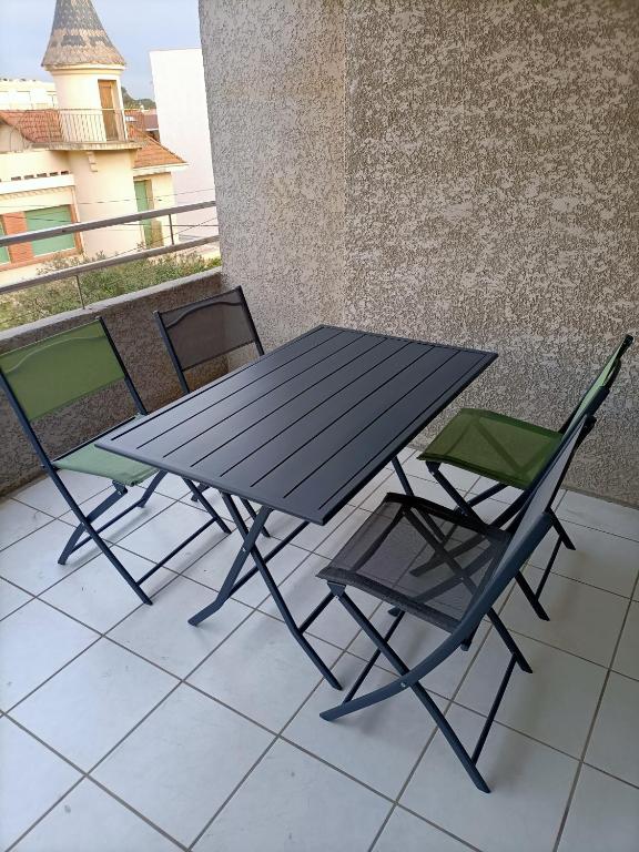 une table de pique-nique et deux chaises sur un balcon dans l'établissement Canet en Roussillon appartement 4 pers proche plage, à Canet