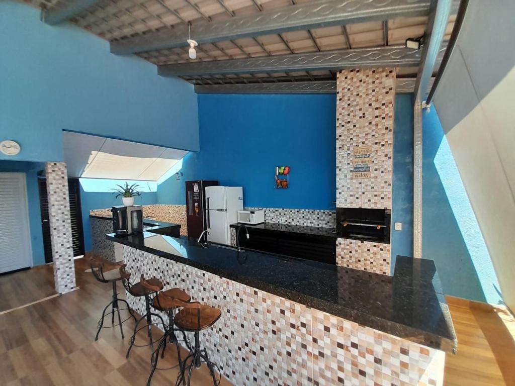 uma cozinha com paredes azuis e um balcão com bancos em Espaço céu Azul em Ribeirão Preto