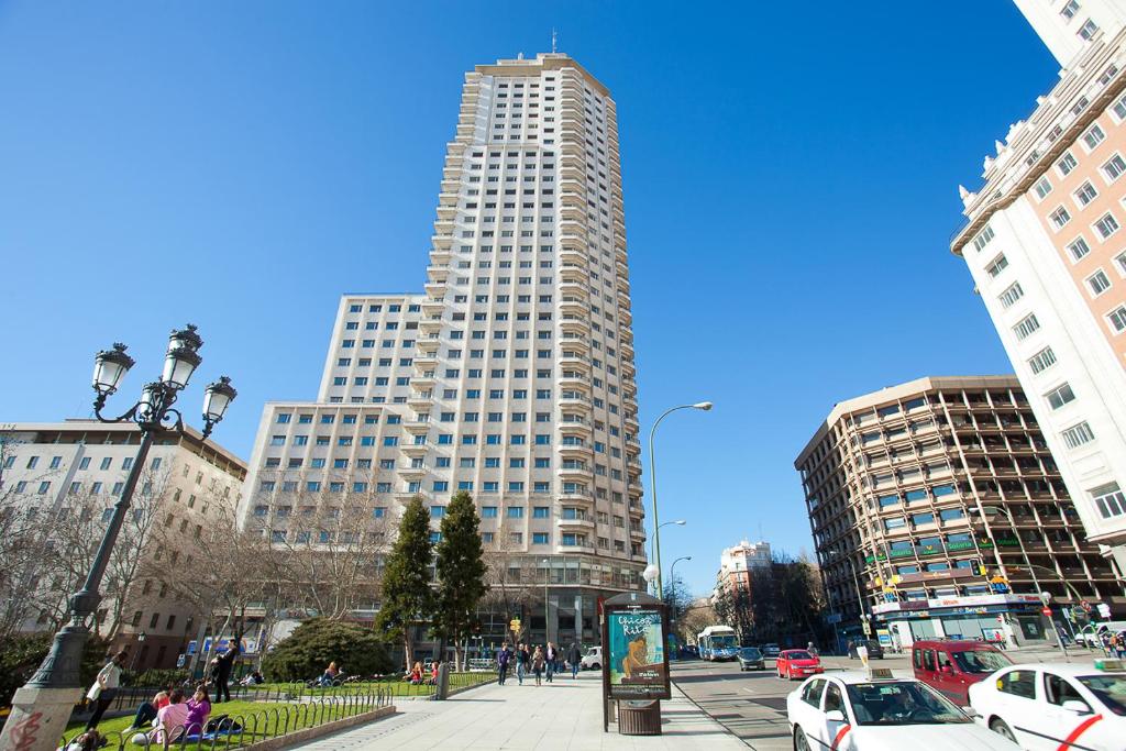 a tall white building with cars parked in a city at Homeclub Exclusive Flat at Madrid Tower in Madrid