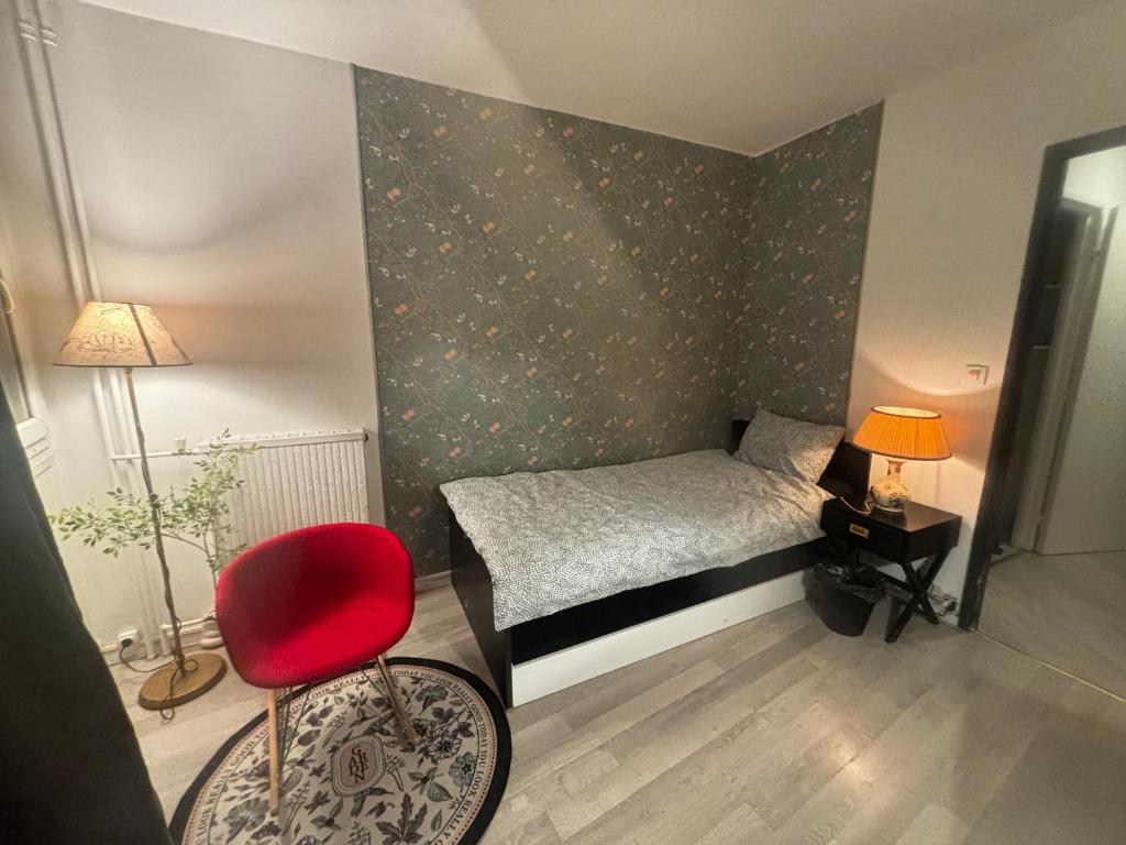 a small bedroom with a bed and a red chair at Métro 8,grand balcon,garage,ascenseur,belle vue pouvoir voir Tour Eiffel in Créteil