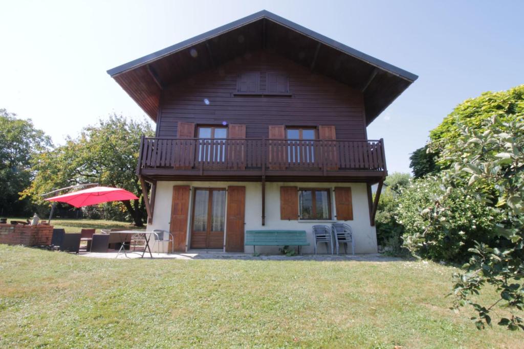 uma casa com uma varanda e um guarda-chuva vermelho em Comfortable family chalet 5 min drive from the lake em Viviers-du-Lac