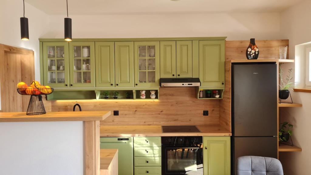 a kitchen with green cabinets and a black refrigerator at Apartments Crljen in Brodarica