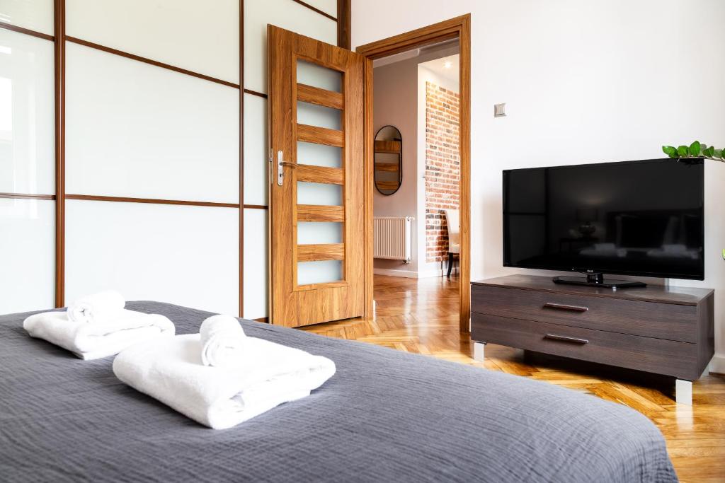um quarto com uma televisão de ecrã plano e uma cama em Househost Apartment: Józefa 2/10 em Cracóvia