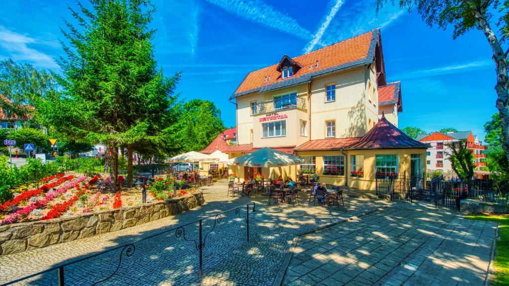 a large building with a garden in front of it at Hotel Kryształ in Świeradów-Zdrój