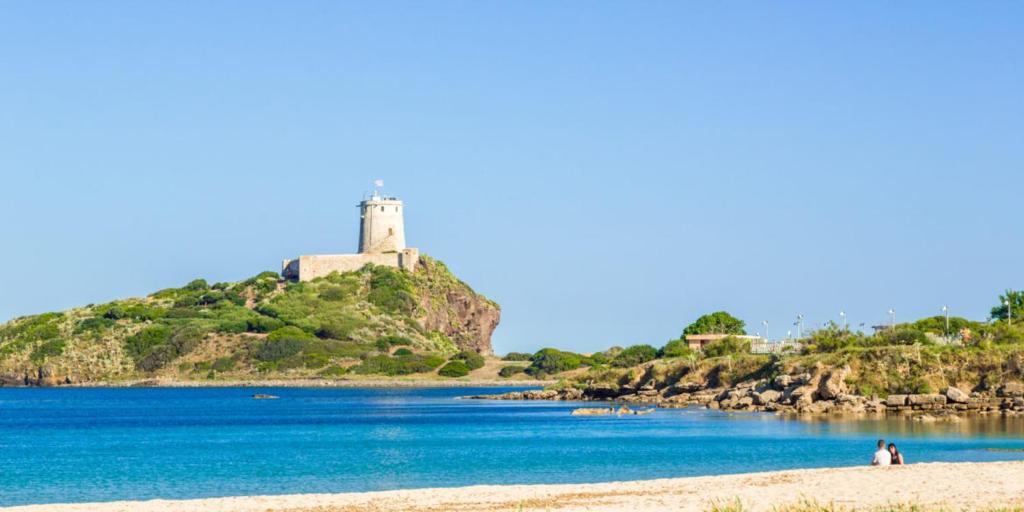 a beach with a lighthouse on an island in the water at Zurrundeddu House in Pula