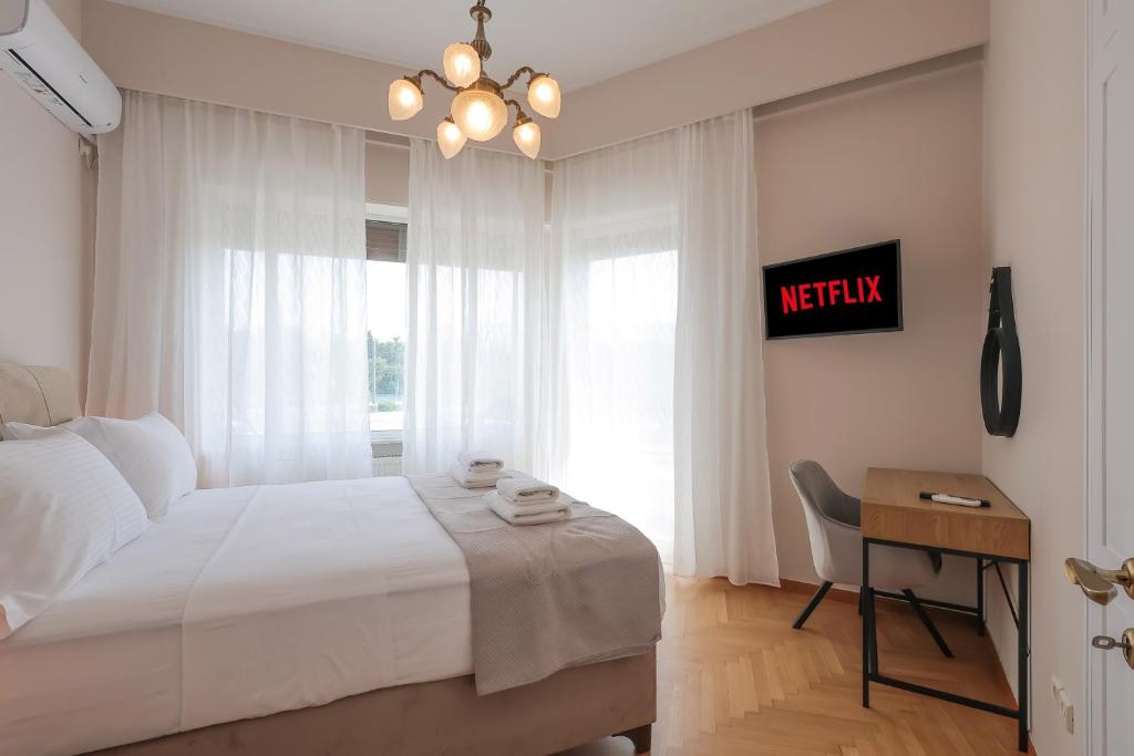 1 dormitorio con cama, escritorio y ventana en Olympic Zeus Apartment en Atenas