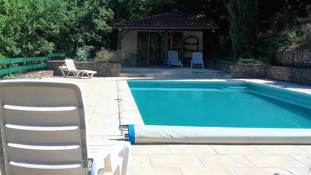 einen Pool mit einem Stuhl, einem Tisch und einem Stuhl in der Unterkunft Villa de 4 chambres avec piscine privee jardin clos et wifi a Milhars in Milhars