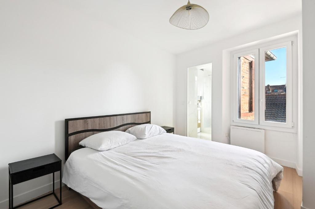 um quarto branco com uma cama grande e uma janela em Cozy T2 + Cuisine - cœur d'Arpajon em Arpajon