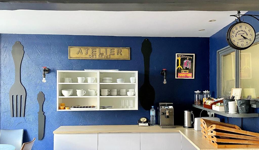 a kitchen with a blue wall with a white cabinet at Hotel Abat Jour in Nantes