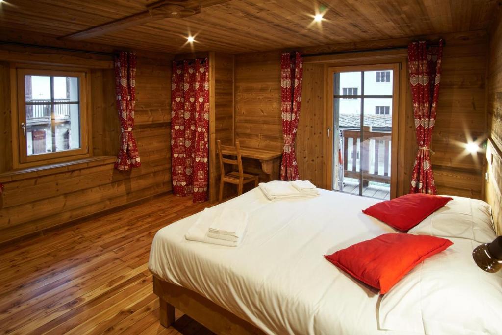 una camera da letto con un grande letto bianco con cuscini rossi di Chalet du Paradis a Cogne