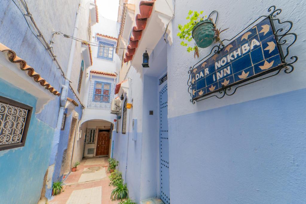 an alley with a sign on the side of a building at DAR NOKHBA INN in Chefchaouen