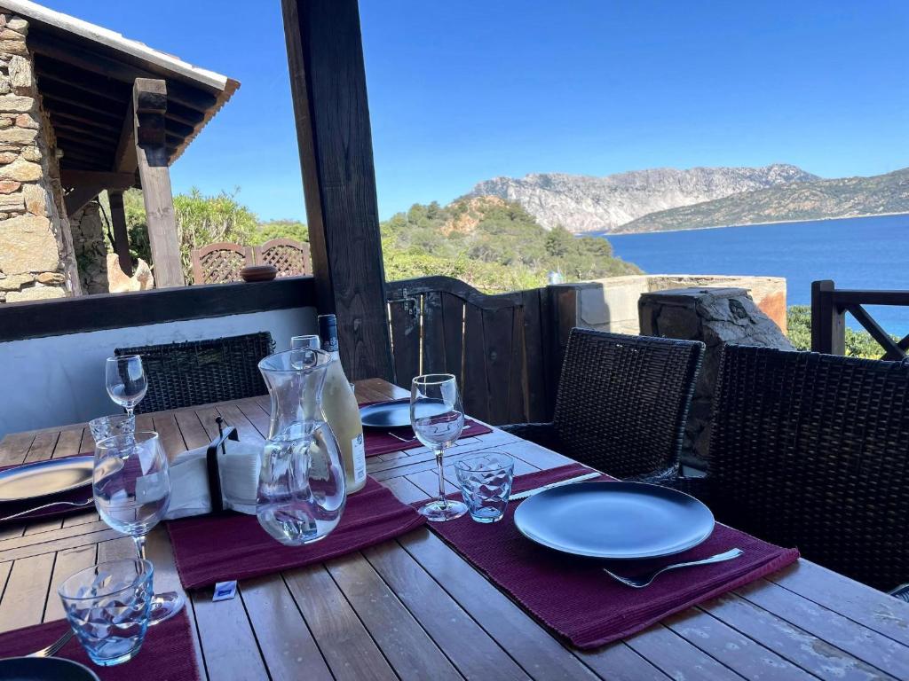 una mesa con copas de vino y platos en una terraza en Punta Est Trilocale Stupenda Vista Mare, en Capo Coda Cavallo