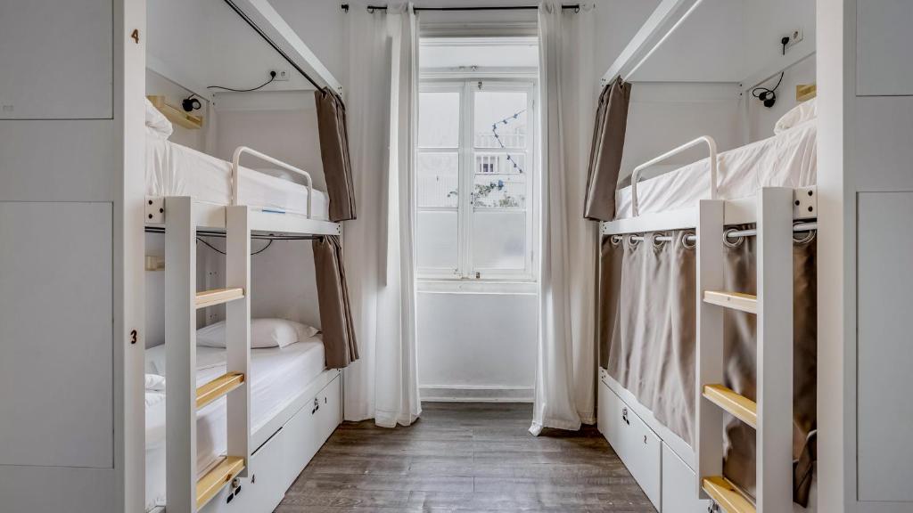 a bedroom with two bunk beds and a window at Hostel Casa d'Alagoa in Faro