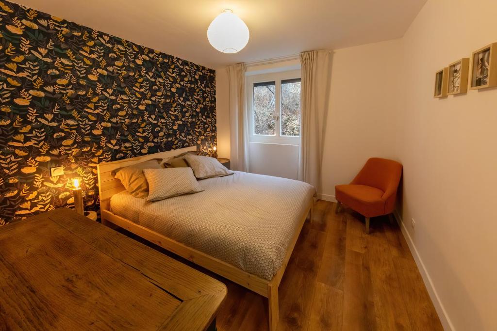 a bedroom with a bed and a chair and a window at Les Appartements de Clélia in Ax-les-Thermes