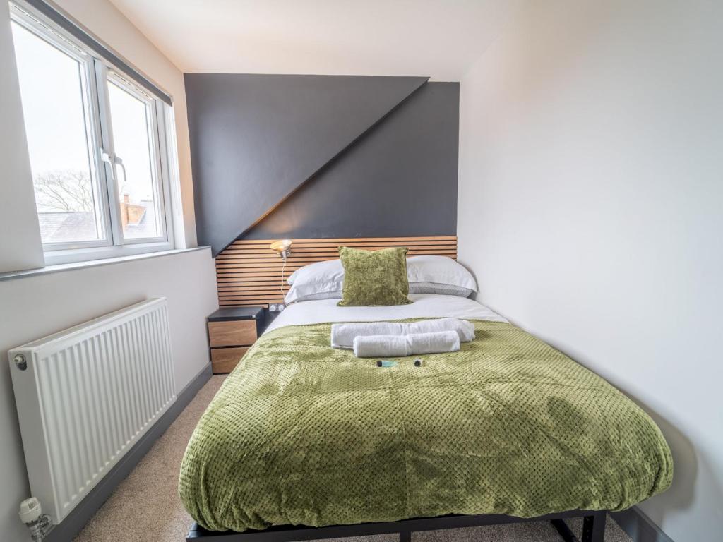 een slaapkamer met een bed met een groene deken bij Sophisticated private getaway Pass the Keys in Beeston