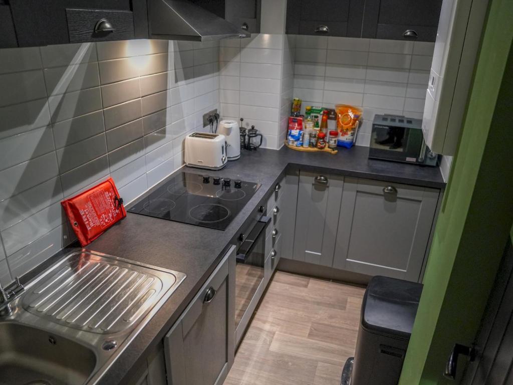 a small kitchen with a sink and a stove at Sophisticated private getaway Pass the Keys in Beeston