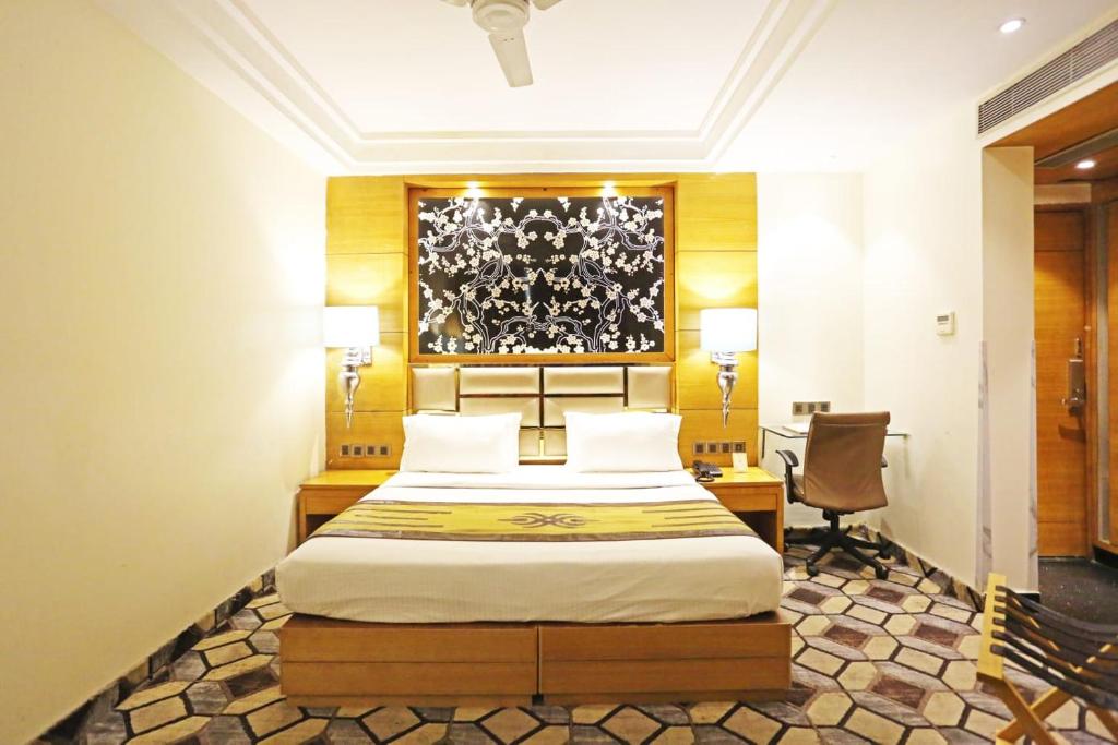 a bedroom with a bed and a desk and a chair at Airport Hotel Claytone in New Delhi