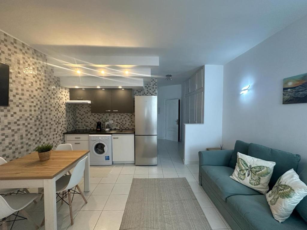 a living room with a blue couch and a kitchen at Liwia beautiful apartment in the first Oceanline in Los Cristianos. in Los Cristianos