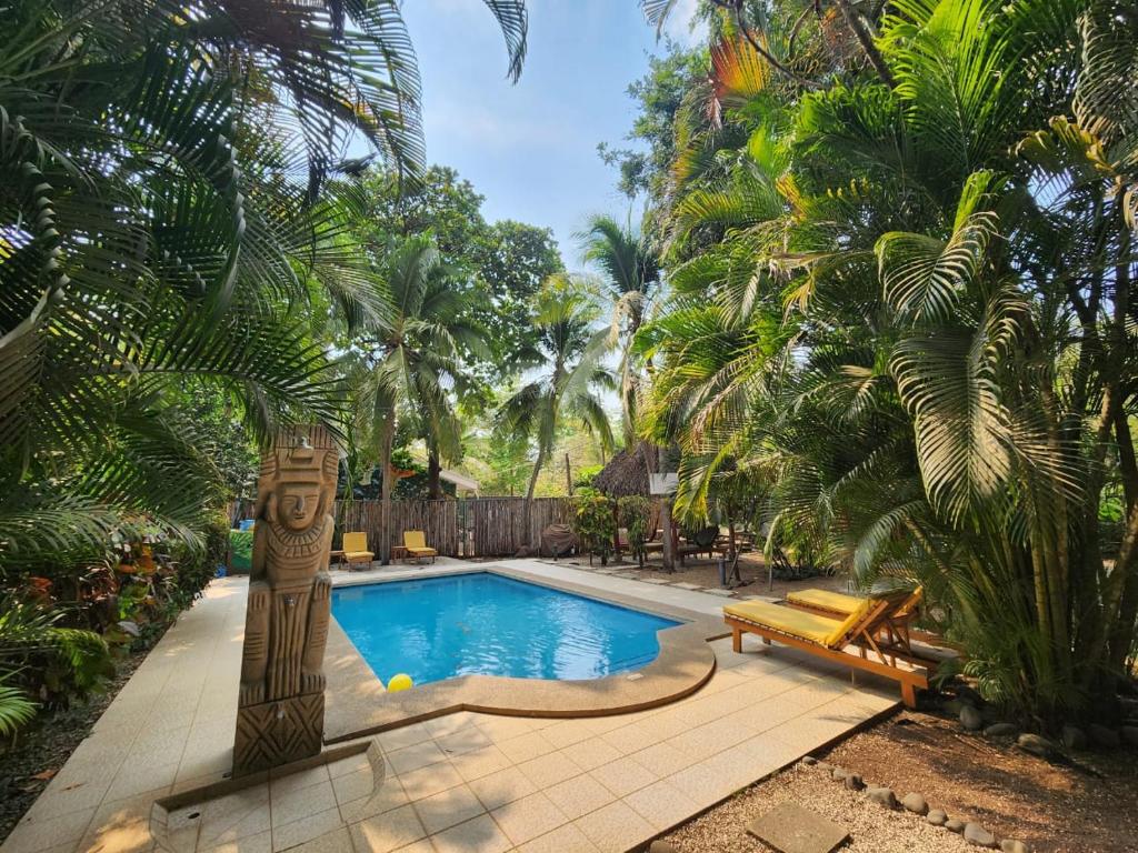 einen Pool in einem Garten mit Palmen in der Unterkunft Villas Pura Vibra in Potrero