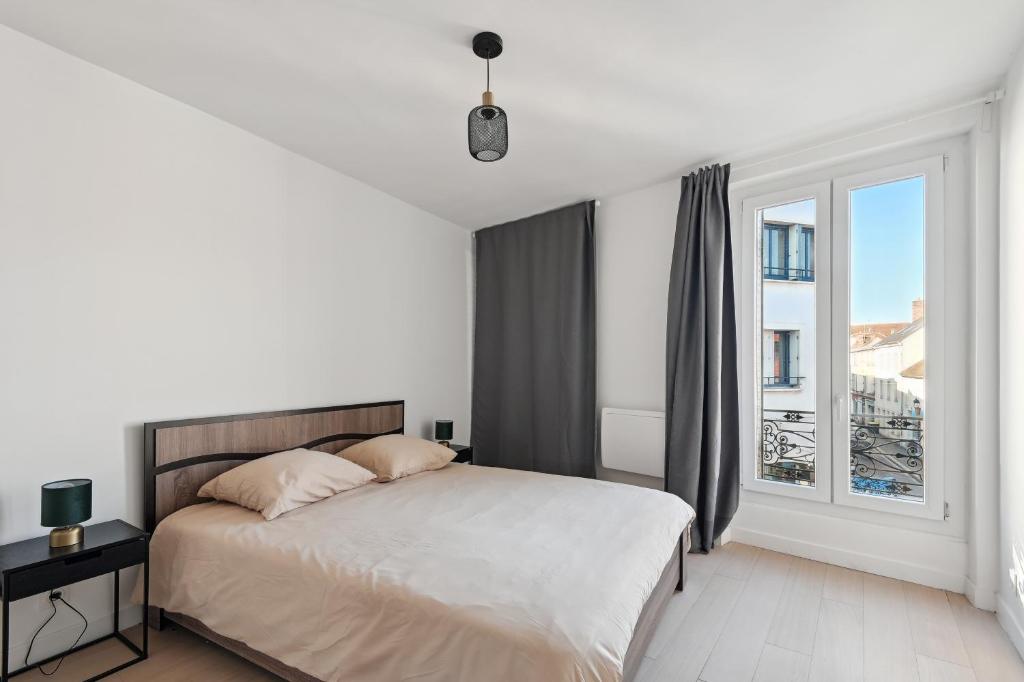 een witte slaapkamer met een bed en een raam bij Charmant T2 - Coeur d'Arpajon in Arpajon