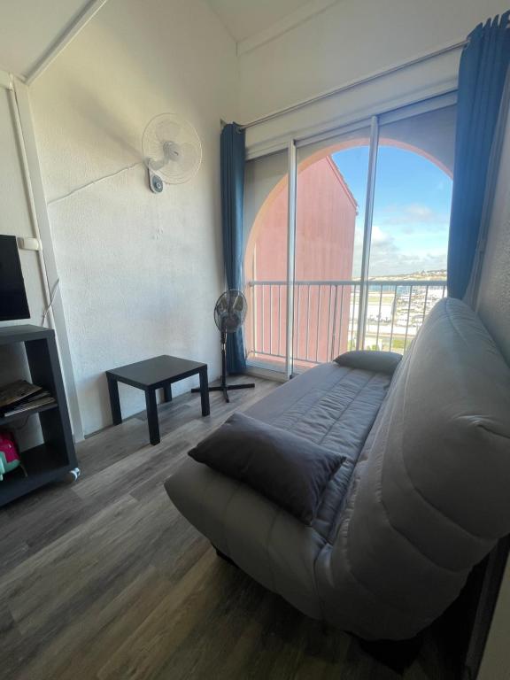 un salon avec un canapé et une grande fenêtre dans l'établissement Appartement lumineux - 7 personnes - Falaises - Port - Parking, au Cap d'Agde