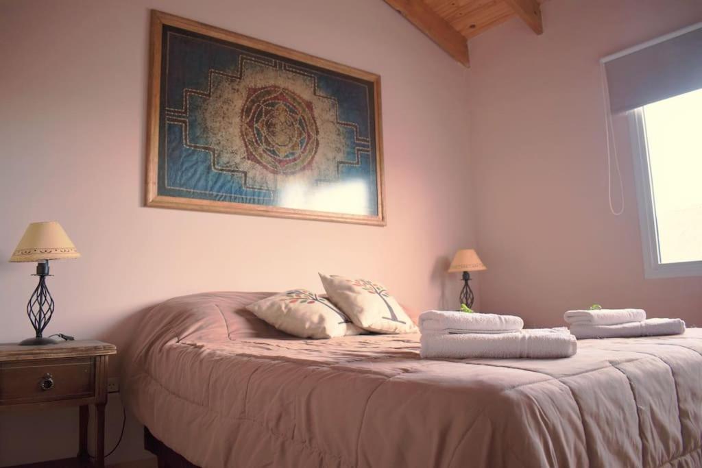 Un dormitorio con una cama con dos almohadas encima. en Olivia Ushuaia Duplex, en Ushuaia