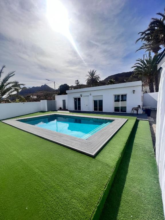 a swimming pool with green grass next to a house at Casa Mayra in Los Caparroses