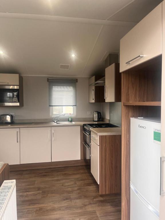 a kitchen with white appliances and wooden cabinets at Seton sands caravan rental in Port Seton