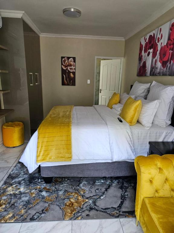 een slaapkamer met een groot wit bed met gele kussens bij Fezeu's On Long Boutique Guest House in Johannesburg