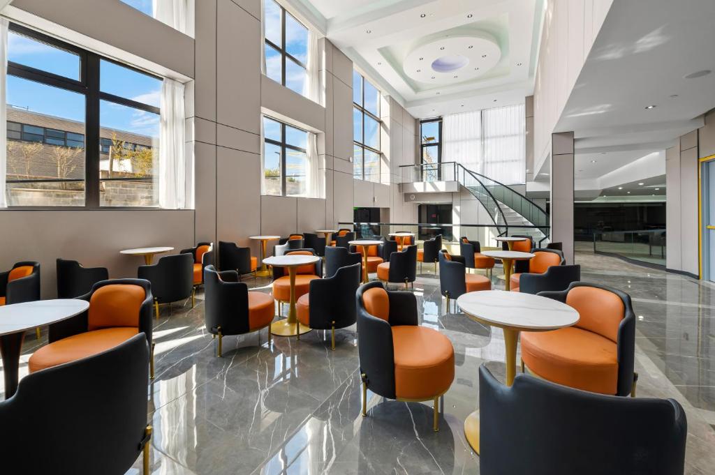 a cafeteria with tables and chairs and windows at Ly New York Hotel in College Point