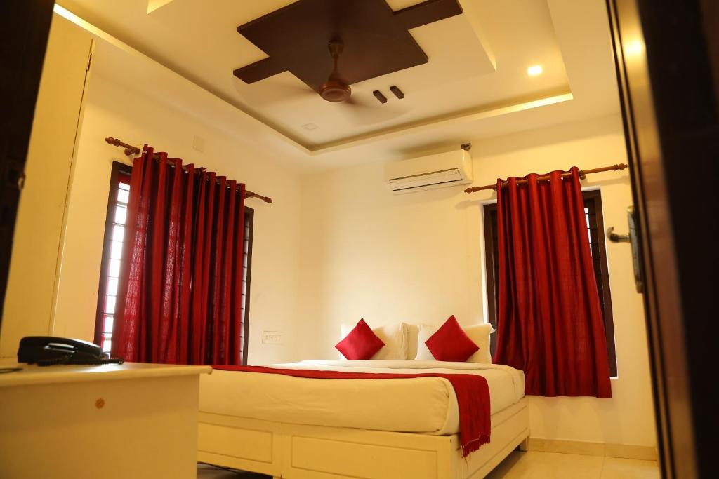 a bedroom with a bed with red curtains at Ritzy Village Residency in Cochin