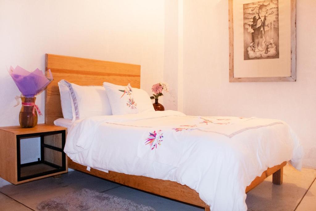 - une chambre dotée d'un lit avec des draps blancs et des fleurs dans l'établissement Hospedaje Donaji, à Oaxaca