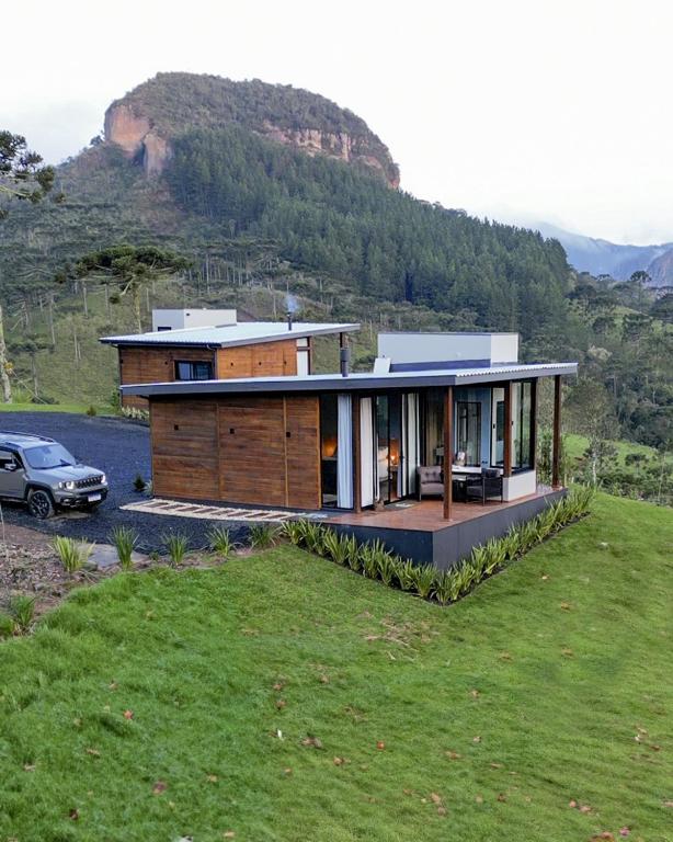 a house on top of a hill with a car at Cabanas Parador do Rei in Urubici